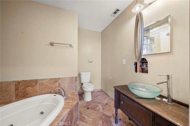 bathroom with vanity, toilet, and tiled tub