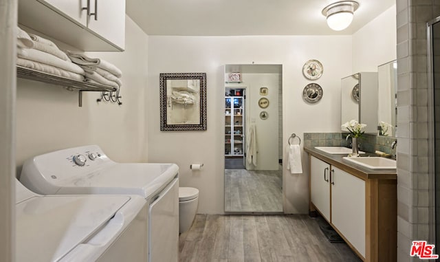 washroom featuring sink, washing machine and dryer, and light hardwood / wood-style floors