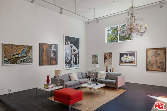 living room with rail lighting, a high ceiling, a chandelier, and dark hardwood / wood-style floors