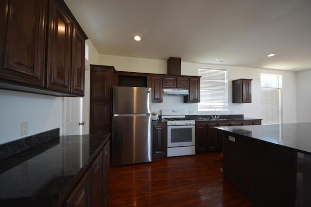 kitchen featuring stainless steel refrigerator, dark hardwood / wood-style flooring, dark stone countertops, and white gas range oven