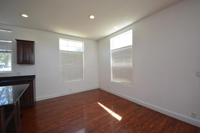 unfurnished dining area with dark wood-type flooring