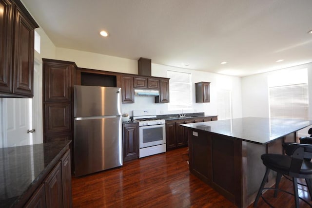 kitchen with a center island, sink, dark hardwood / wood-style floors, white range with gas stovetop, and stainless steel refrigerator