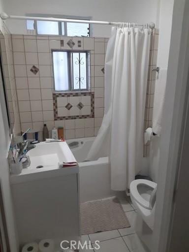 full bathroom featuring toilet, vanity, tile patterned flooring, and shower / bathtub combination with curtain