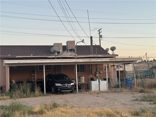 back house at dusk featuring a carport