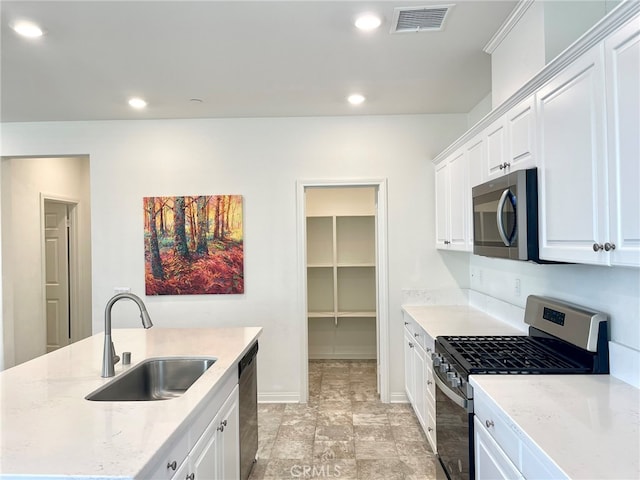 kitchen with light stone counters, stainless steel appliances, sink, and white cabinets