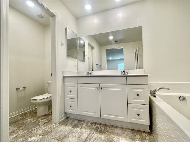 bathroom featuring vanity, toilet, and tiled bath