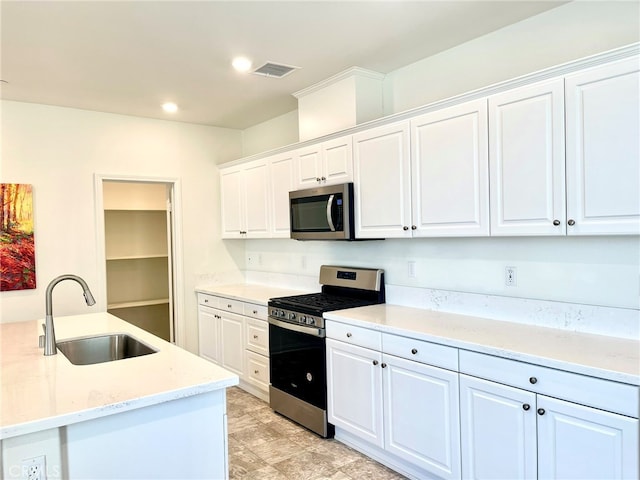 kitchen with light stone countertops, sink, stainless steel appliances, white cabinets, and light hardwood / wood-style flooring