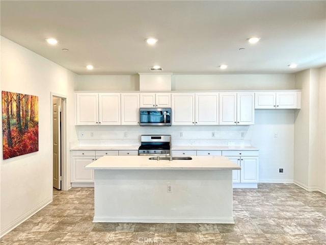 kitchen featuring appliances with stainless steel finishes, sink, a center island with sink, and white cabinets