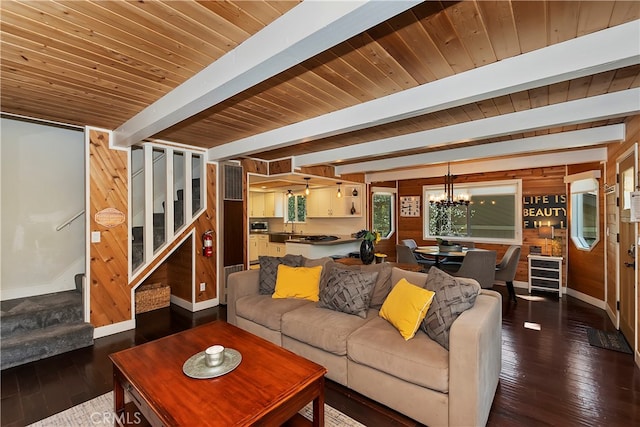 living room with beamed ceiling, dark wood-type flooring, wooden ceiling, an inviting chandelier, and wood walls