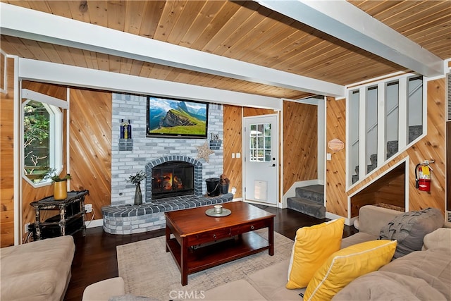 living room with wood walls, beamed ceiling, a brick fireplace, and hardwood / wood-style floors