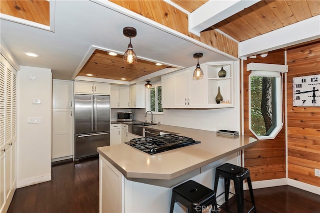 kitchen featuring kitchen peninsula, white cabinetry, stainless steel appliances, and hanging light fixtures