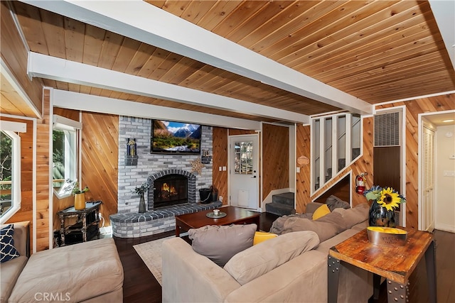 living room with beam ceiling, wood walls, wooden ceiling, and a brick fireplace