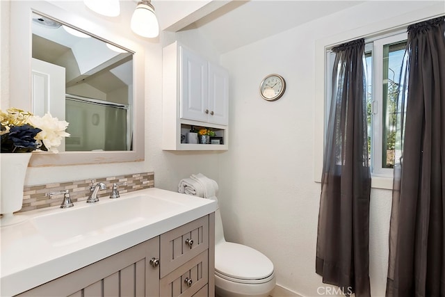 bathroom with vanity, decorative backsplash, toilet, and plenty of natural light