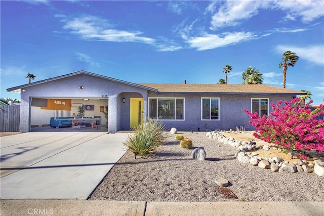 ranch-style home with driveway, an attached garage, fence, and stucco siding