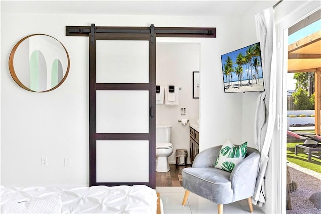 bedroom featuring ensuite bath, access to exterior, and a barn door