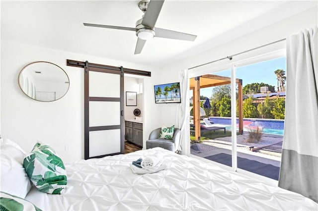 bedroom with a barn door, a ceiling fan, access to outside, and connected bathroom