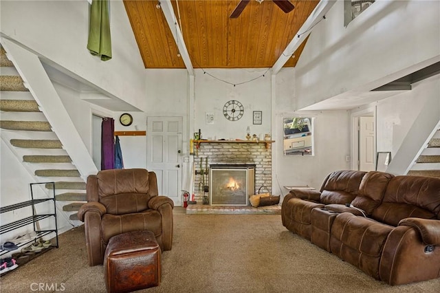 living room featuring carpet flooring, a towering ceiling, a brick fireplace, and ceiling fan