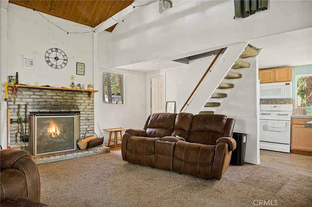 living room featuring a fireplace, light hardwood / wood-style flooring, high vaulted ceiling, and wooden ceiling