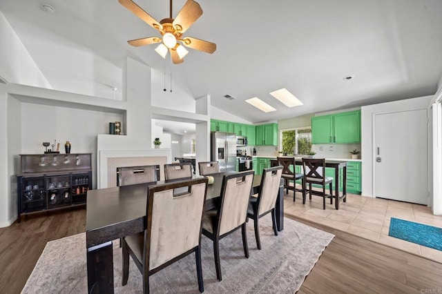 dining space with ceiling fan, wood-type flooring, lofted ceiling, and a fireplace