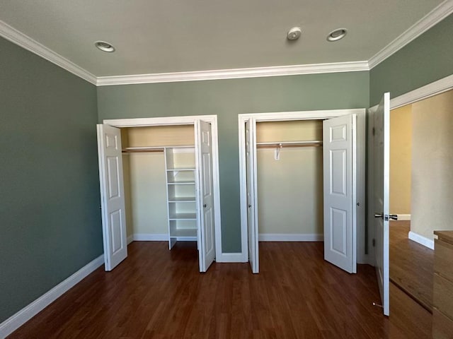 unfurnished bedroom featuring dark hardwood / wood-style flooring, crown molding, and multiple closets