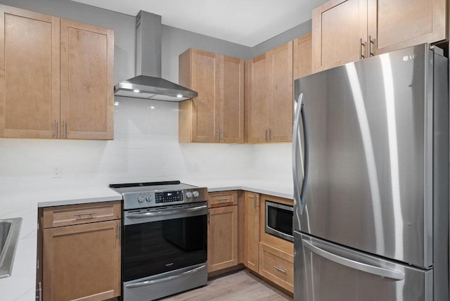 kitchen featuring wall chimney range hood, light hardwood / wood-style flooring, stainless steel appliances, and backsplash