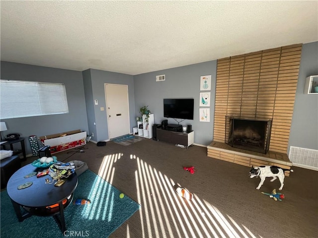 living room with carpet floors, a brick fireplace, and a textured ceiling