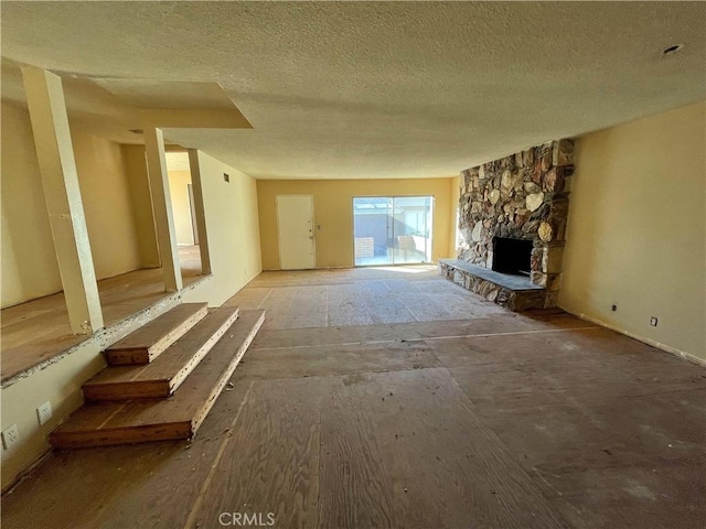 unfurnished living room featuring a stone fireplace and a textured ceiling