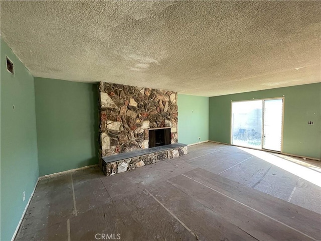 unfurnished living room with a stone fireplace and a textured ceiling