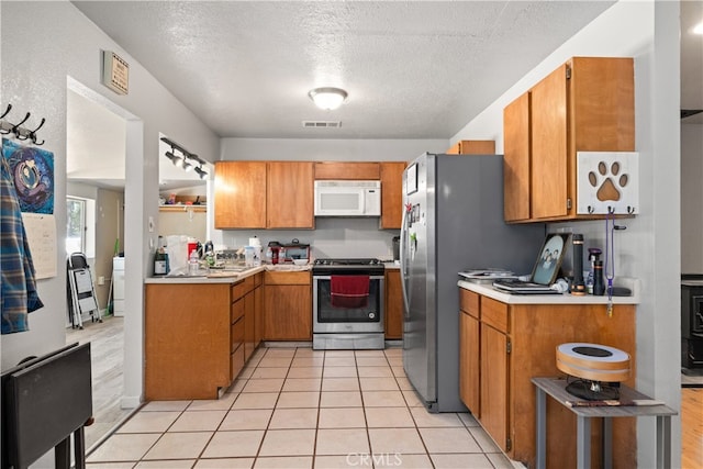 kitchen featuring appliances with stainless steel finishes, a textured ceiling, washer / dryer, and light hardwood / wood-style floors