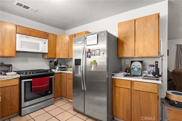 kitchen with a textured ceiling, stainless steel appliances, and light tile patterned floors