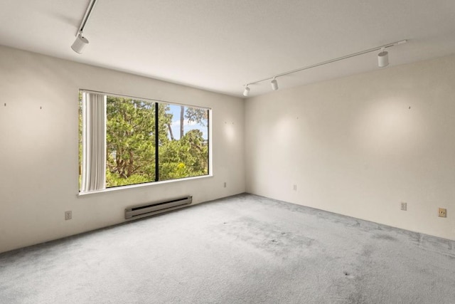 unfurnished room featuring baseboard heating, carpet, and rail lighting