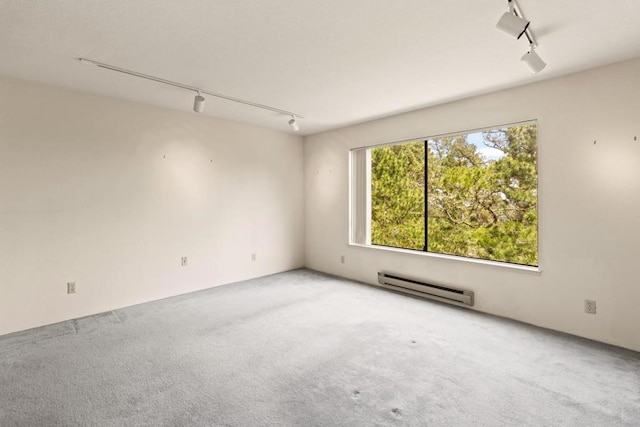 carpeted spare room featuring rail lighting and a baseboard radiator