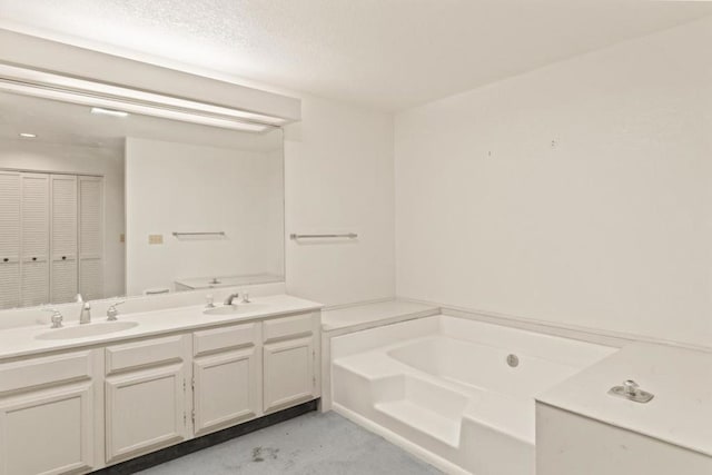 bathroom with a textured ceiling, a bathtub, and vanity