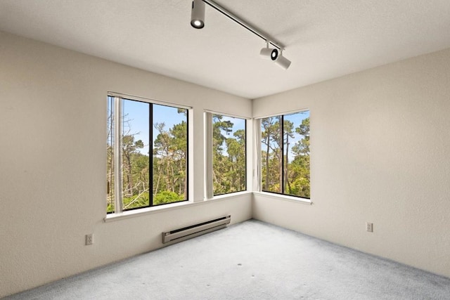 spare room with baseboard heating, track lighting, and carpet flooring