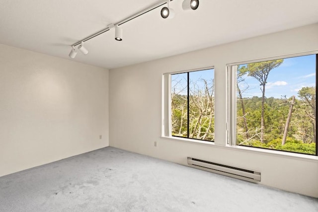 carpeted spare room featuring track lighting and a baseboard radiator