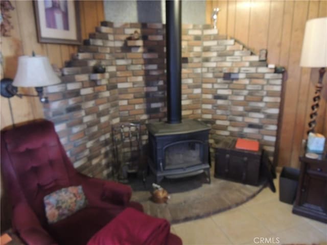 tiled living room with wood walls and a wood stove