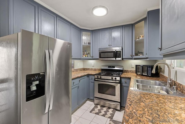 kitchen with dark stone countertops, sink, crown molding, light tile patterned floors, and appliances with stainless steel finishes