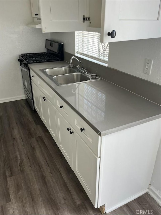 kitchen with white cabinetry, sink, stainless steel gas range, range hood, and dark hardwood / wood-style floors