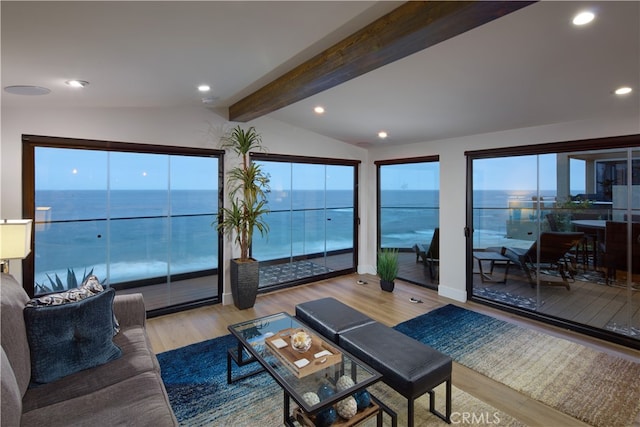 living room with a water view, light hardwood / wood-style flooring, and vaulted ceiling with beams