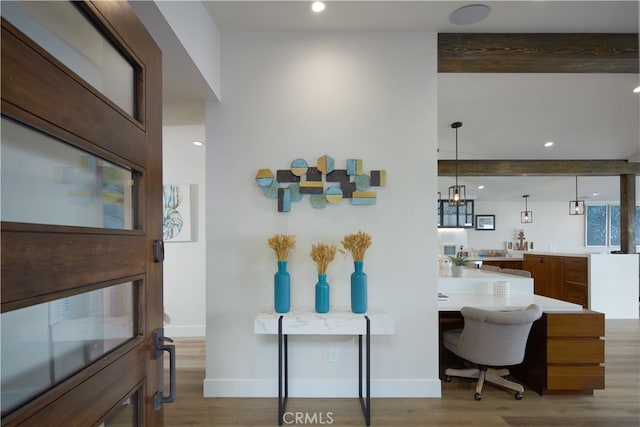 interior space featuring beam ceiling, light hardwood / wood-style flooring, and pendant lighting