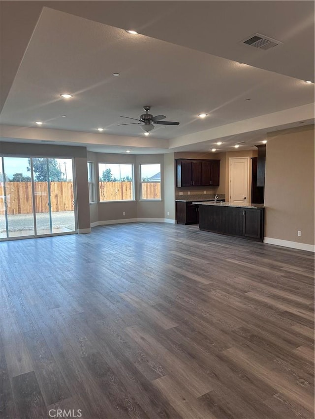 unfurnished living room with ceiling fan and dark wood-type flooring