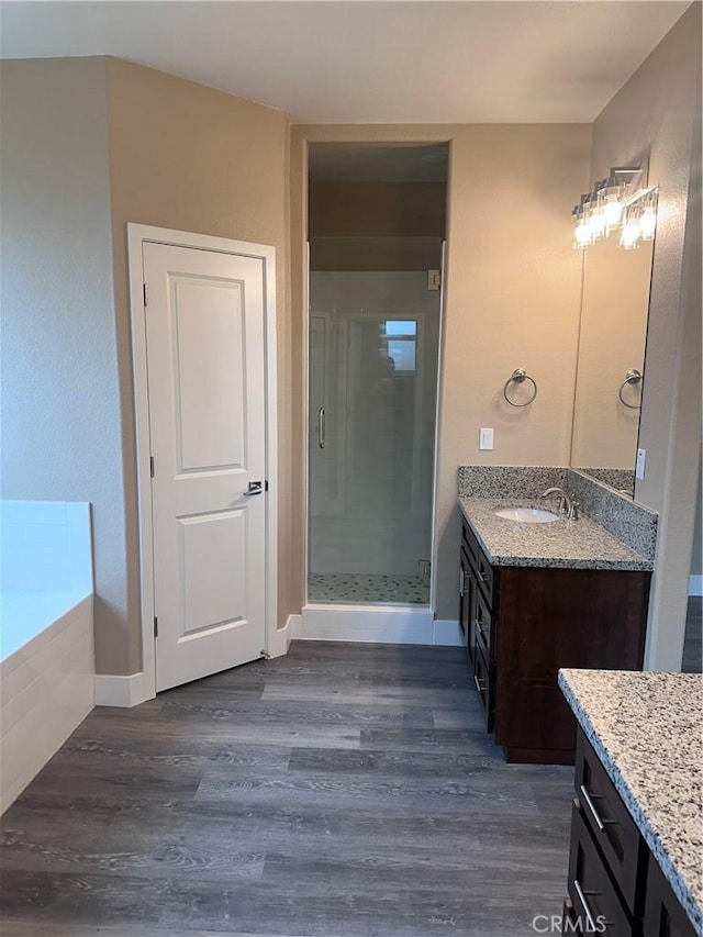 bathroom with hardwood / wood-style flooring, vanity, and plus walk in shower