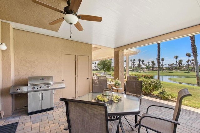 view of patio featuring ceiling fan, a grill, and a water view