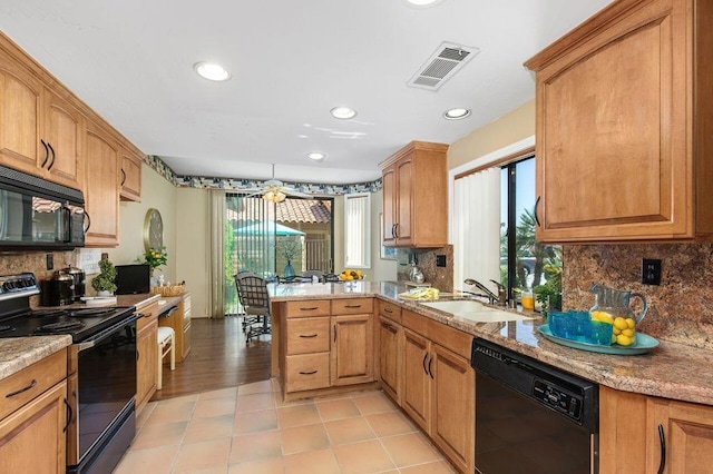 kitchen with kitchen peninsula, decorative backsplash, light stone countertops, sink, and black appliances