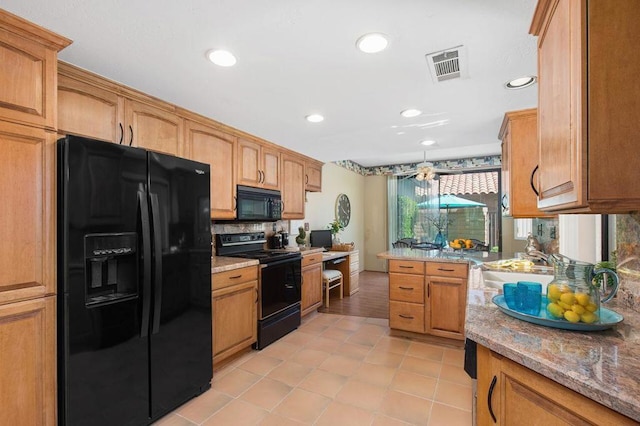 kitchen featuring decorative backsplash, sink, light stone counters, and black appliances