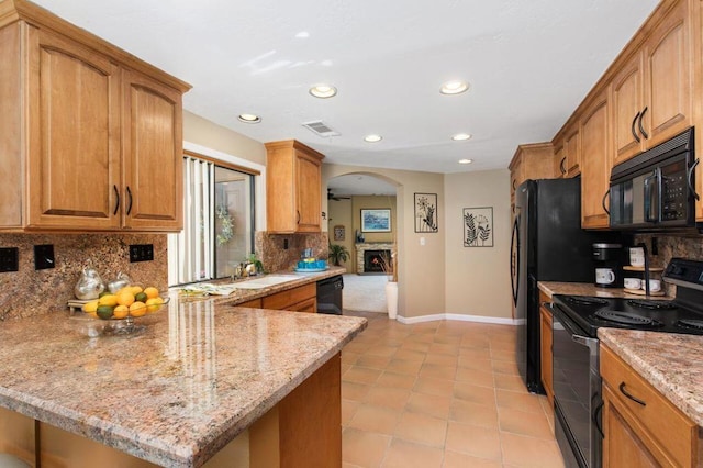 kitchen featuring sink, tasteful backsplash, light stone counters, kitchen peninsula, and black appliances