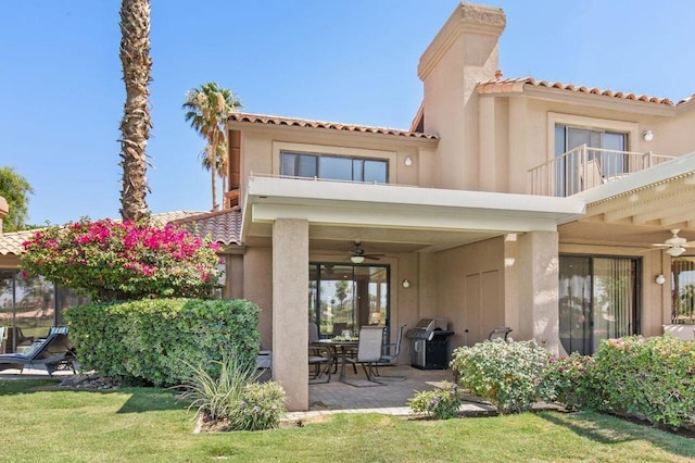 back of house featuring a patio, a balcony, ceiling fan, and a lawn