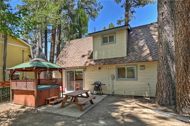 rear view of property with a patio and a hot tub