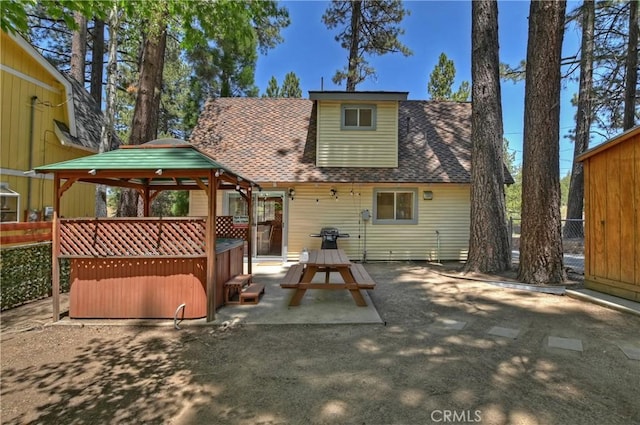 back of property featuring a gazebo, a patio, and a hot tub