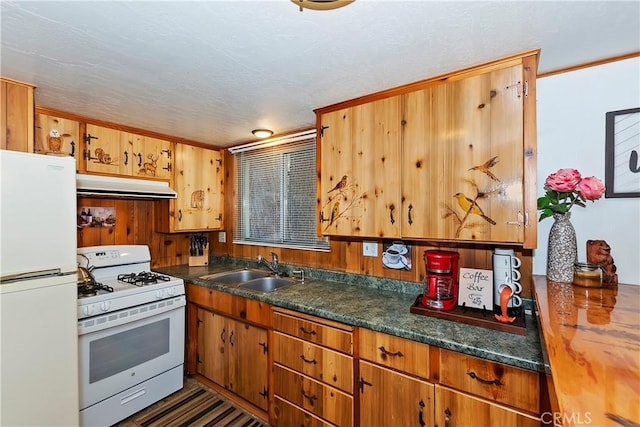 kitchen with a textured ceiling, white appliances, wood walls, and sink